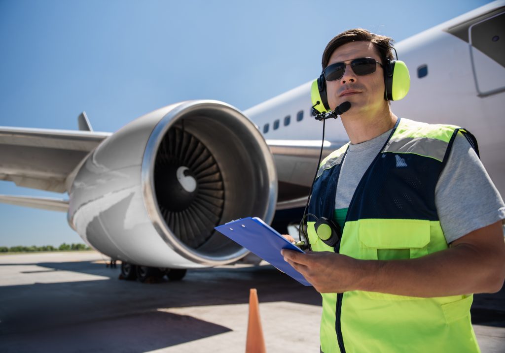 airport worker with clipboard near giant jet engine